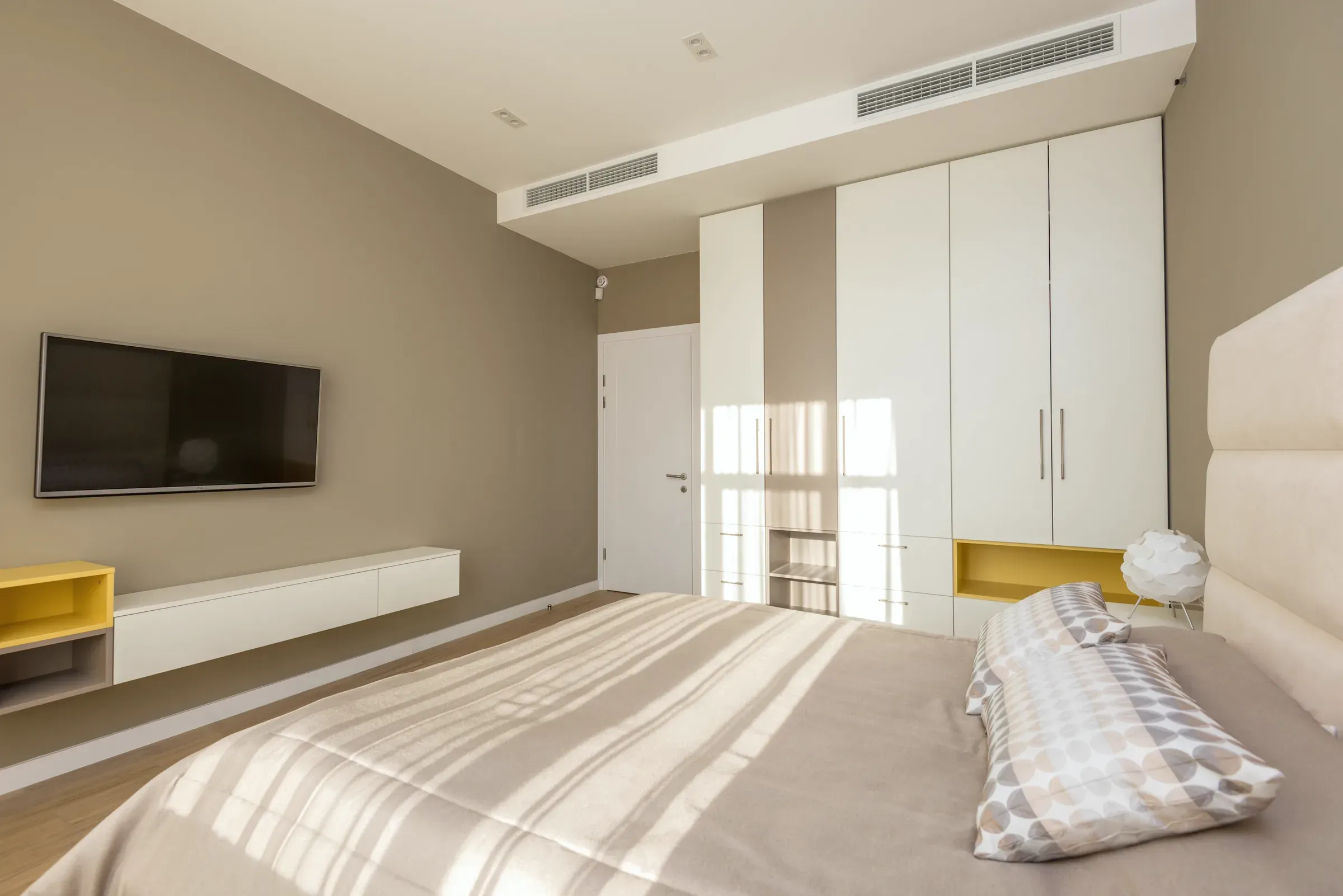Bedroom with a ceiling air slot above a full-wall wardrobe