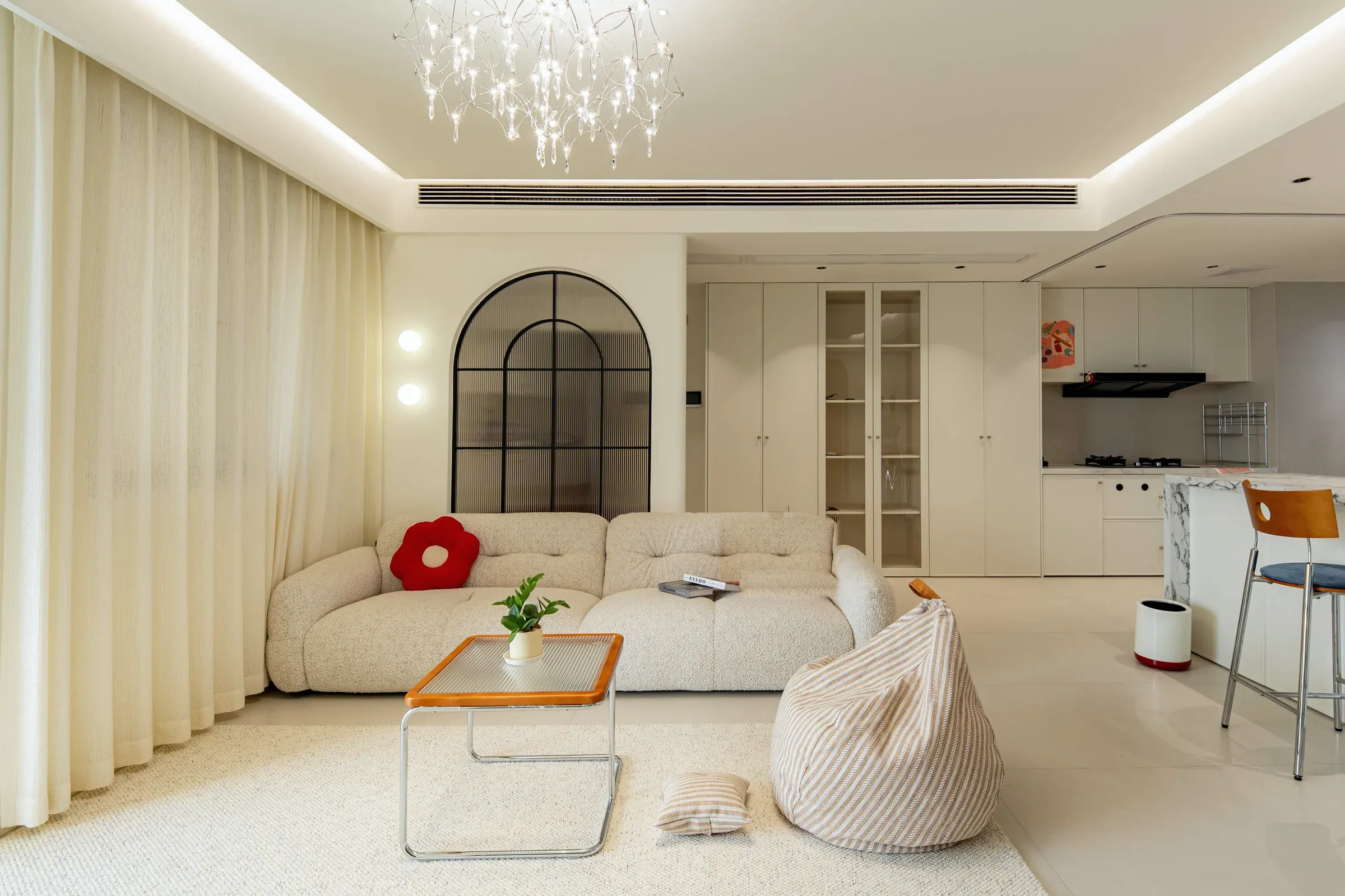 Living room with a linear ceiling air slot, an arched glass entry partition and full-wall built-in cabinets