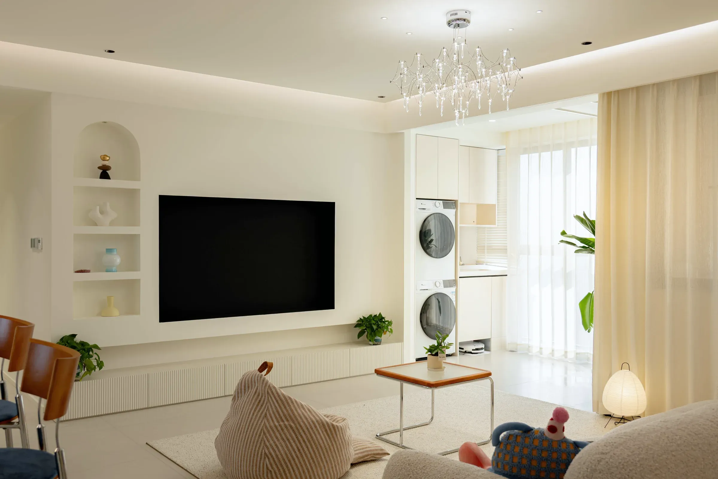 TV wall with niche shelves beside a stacked washer and dryer in its own niche